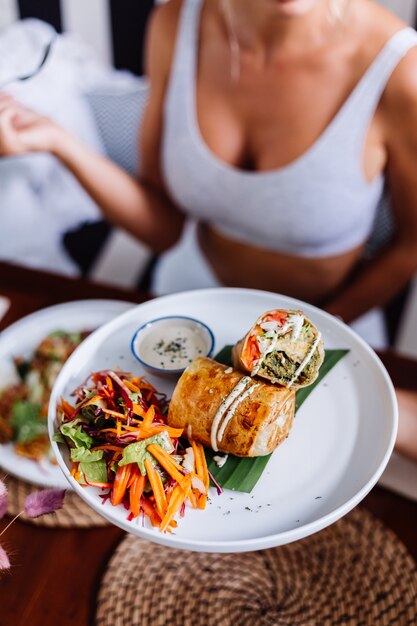 Woman having colorful healthy vegan vegetarian meal salad in summer cafe natural day light