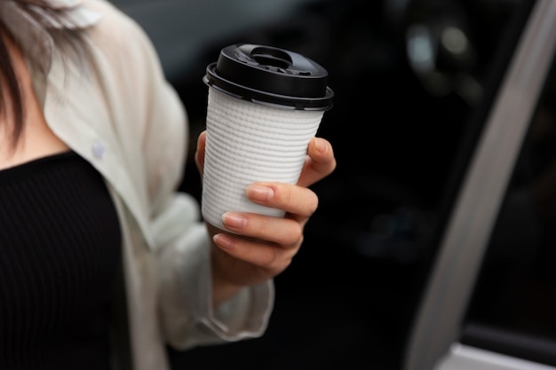 Woman having a cup of coffee with her electric car