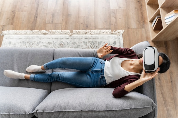 Woman having fun at home on the couch with virtual reality headset