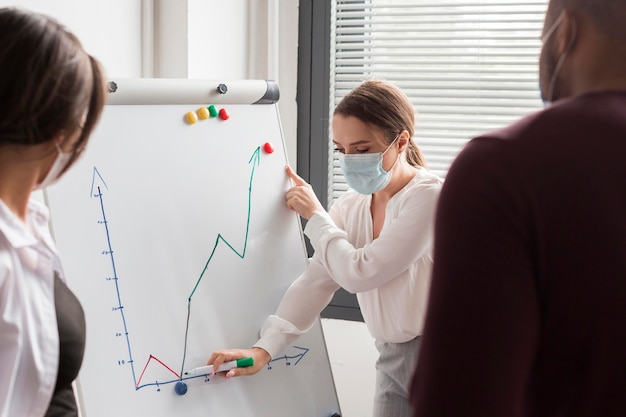 Free Photo woman having a presentation at office during pandemic with mask on