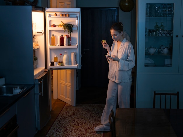 Free Photo woman having snacks at night full shot