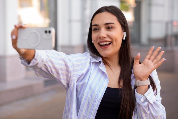 Free photo woman having a videocall on smartphone while out in the city