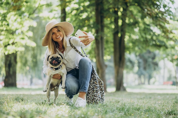 Woman having a walk in park with her pug-dog pet