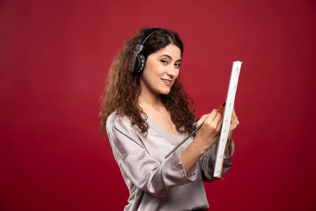 Woman in headphones painting on canvas.