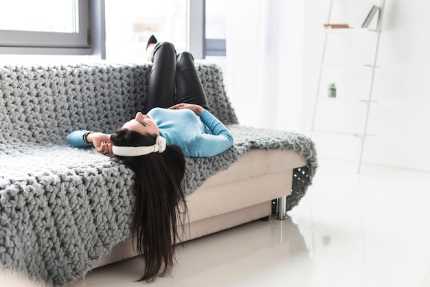 Free photo woman in headphones resting on sofa