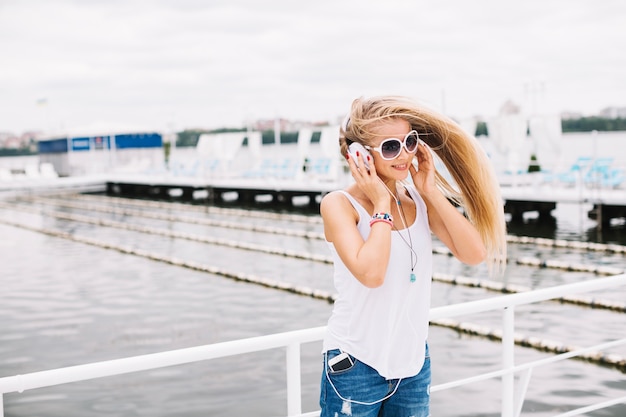 Free Photo woman in headphones shaking head near river