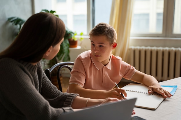 Woman helping boy with homework side view