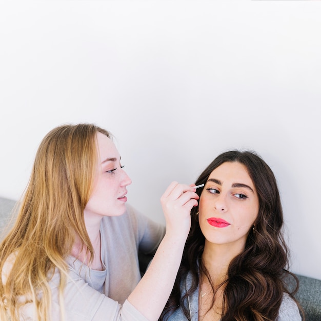 Woman helping friend to apply makeup