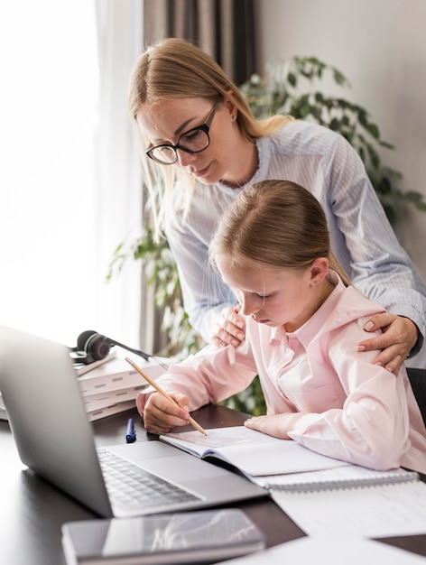 Woman helping a little girl doing her homework