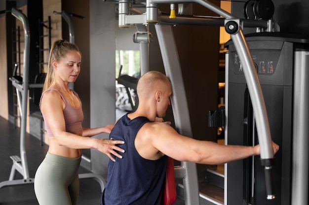 Woman helping man at gym side view