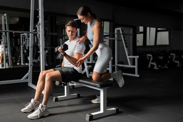 Woman helping man at gym