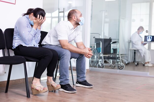 Woman and her husband crying in hospital waiting room