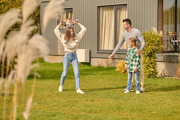 Woman holding baby on neck and man pointing to lawn