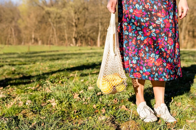 Free Photo woman holding a bag of fruit in the park