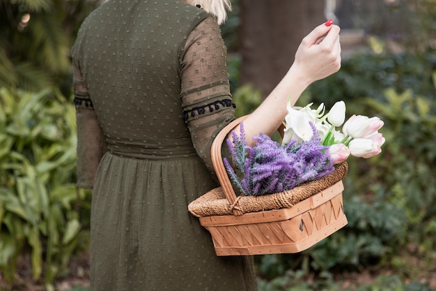 Free photo woman holding basket with flowers