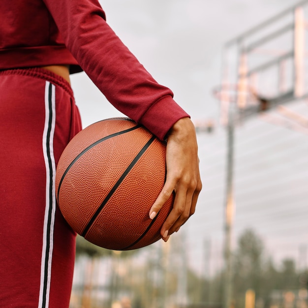 Free photo woman holding a basketball next to her legs