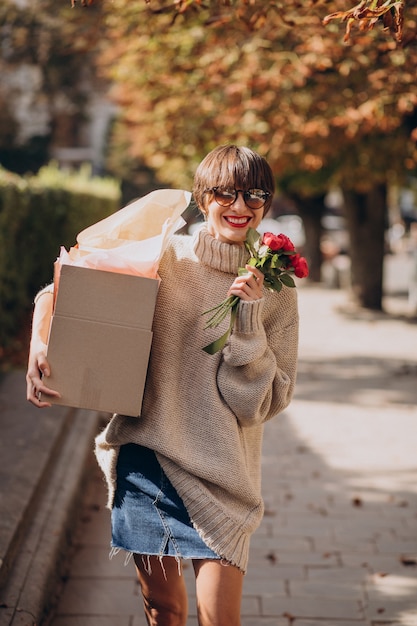 Woman holding big parcel box and walking in the street