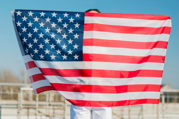 Woman holding big usa flag over herself