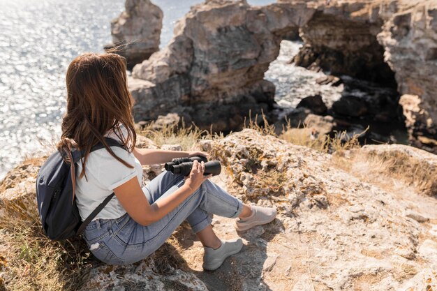 Woman holding binoculars on the beach