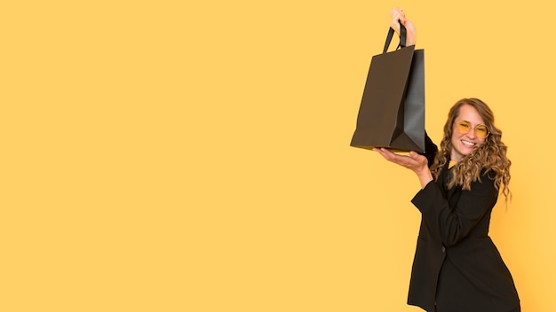 Free photo woman holding a black shopping bag copy space