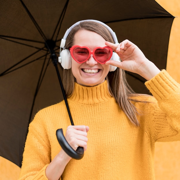 Free Photo woman holding a black umbrella while using headphones