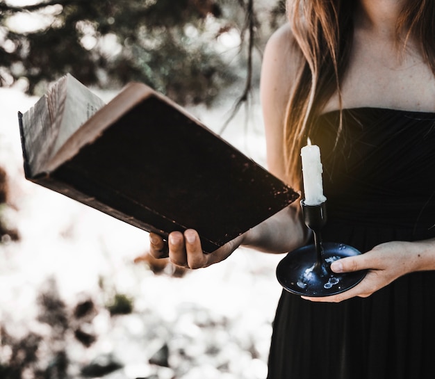 Free photo woman holding book and candle in forest