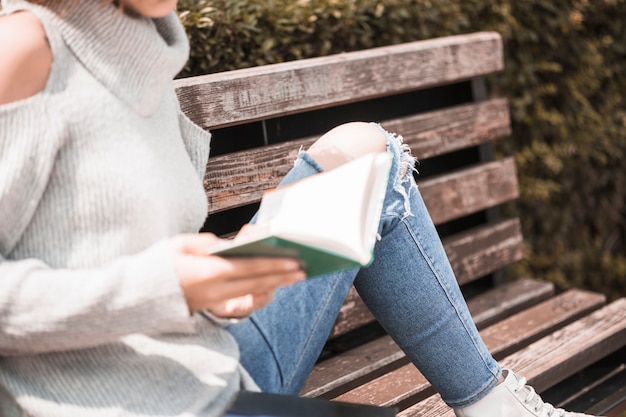 Free photo woman holding book and sitting on bench