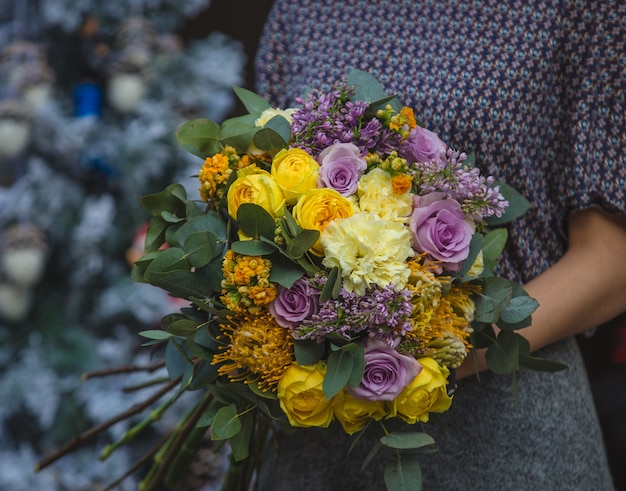 Free photo a woman holding a bouquet of fall autumn color flowers in the hand