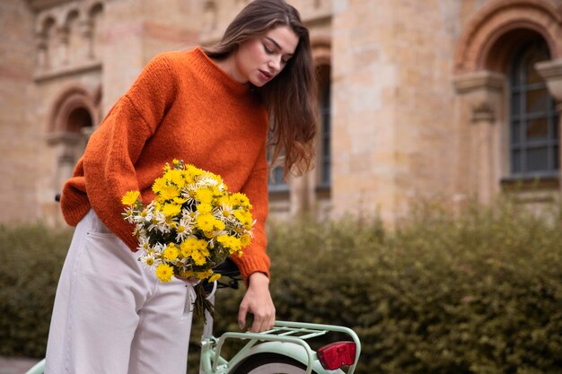 Woman holding bouquet of flowers while sitting next to bicycle