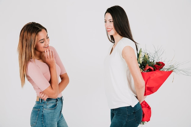 Woman holding bouquet for girlfriend behind back