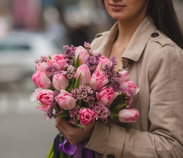 A woman holding a bouquet of pink tulips an sirens in the hand 