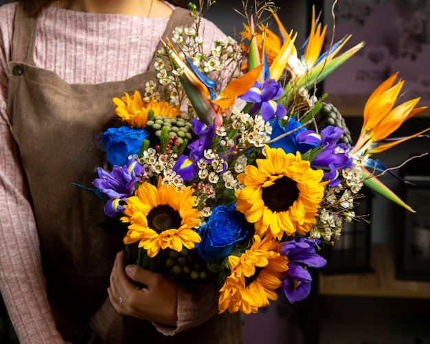 woman holding bouquet of sunflowers iris and blue rose