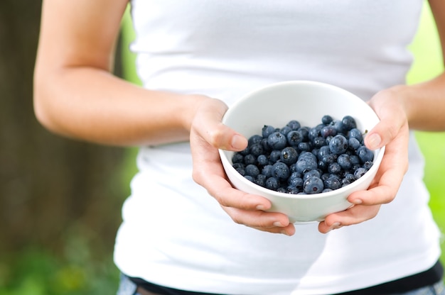 Free Photo woman holding bowl filled blueberries