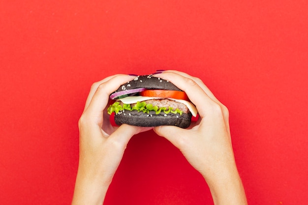 Free photo woman holding burger over red table