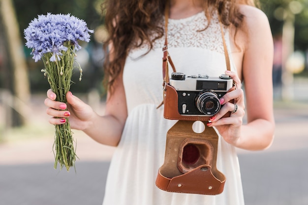 Free photo woman holding camera and flowers