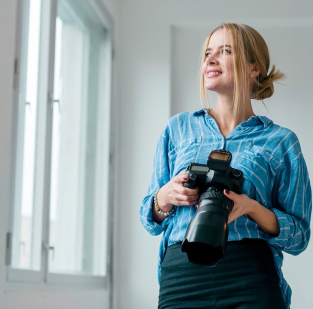 Free photo woman holding a camera and looking through windows