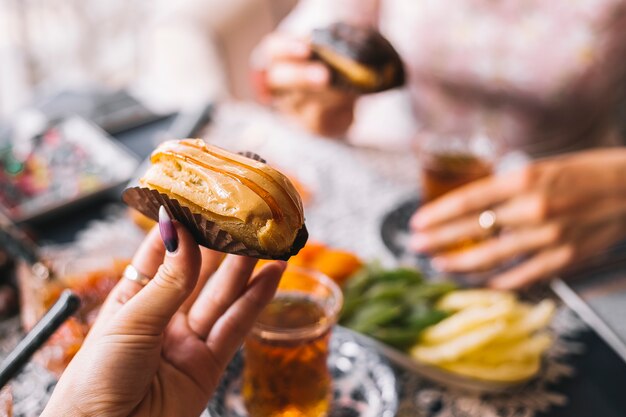 Woman holding caramel eclair served for tea setup