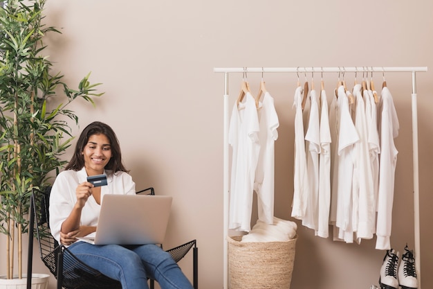 Woman holding a card and working on laptop 