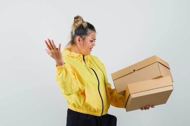 Free Photo woman holding cardboard boxes in sport suit and looking confused. front view.