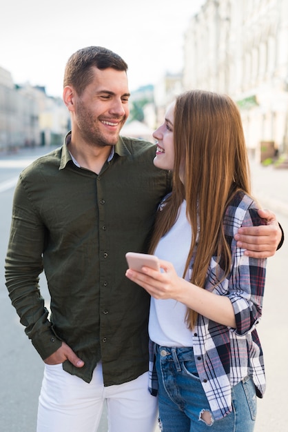 Woman holding cellphone and looking at her boyfriend on street