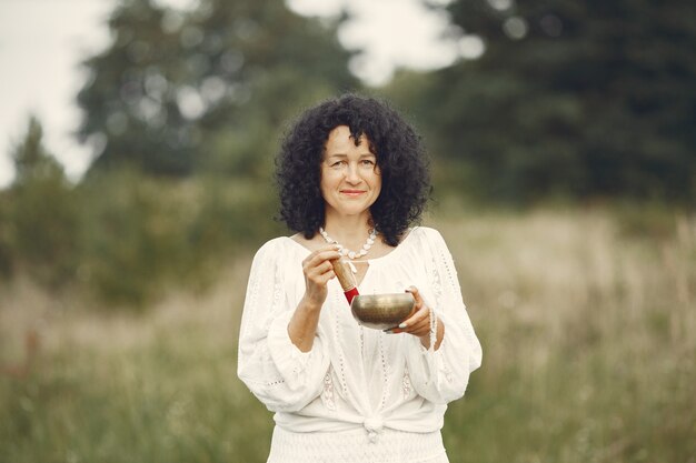 Woman holding chanting bowl in nature setting