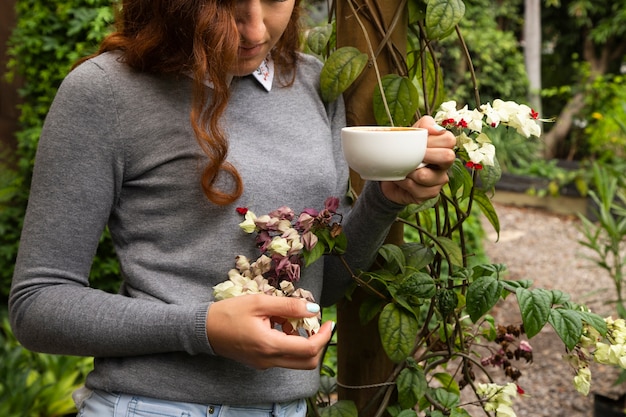 Free photo woman holding a coffee cup and flowers