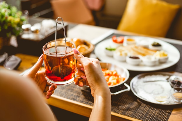 A woman holding cup of black tea and breakfast set on the table