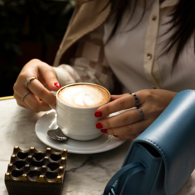 Free photo woman holding cup of cappuccino