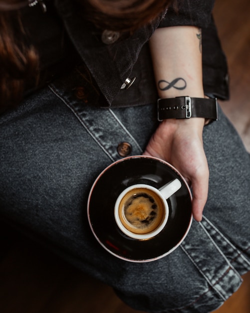 Free photo woman holding a cup of espresso on her legs