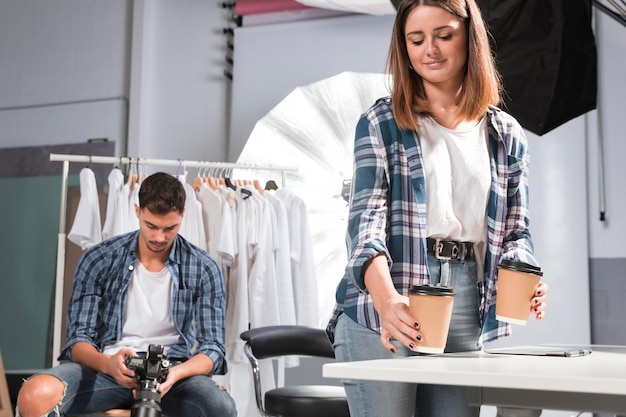 Free photo woman holding cups of coffee next to photographer