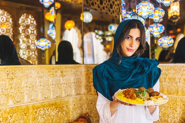 Woman holding dish of arab food