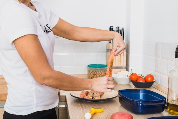 Woman holding fish slice in kitchen