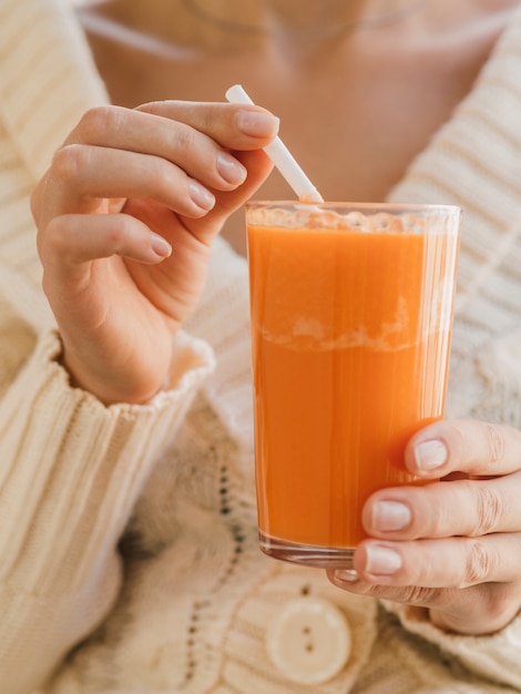 Free photo woman holding glass with organic carrot juice