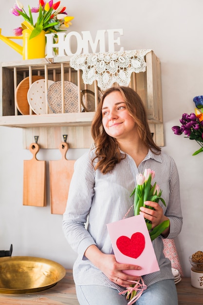 Free photo woman holding greeting card and flowers